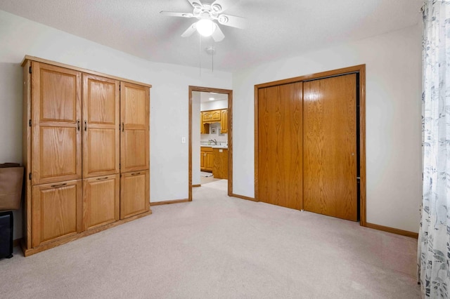 unfurnished bedroom featuring light colored carpet, baseboards, a closet, and ceiling fan