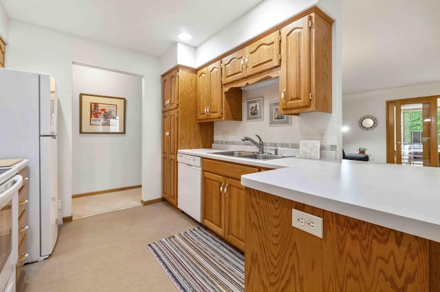 kitchen with a sink, white appliances, light countertops, light flooring, and brown cabinetry