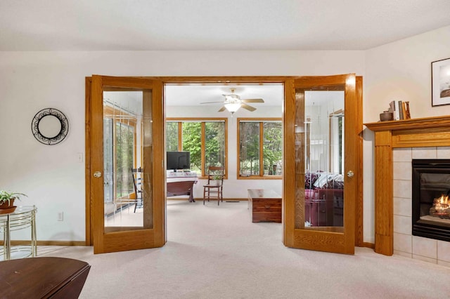 carpeted living area with a desk, a tile fireplace, baseboards, french doors, and a ceiling fan