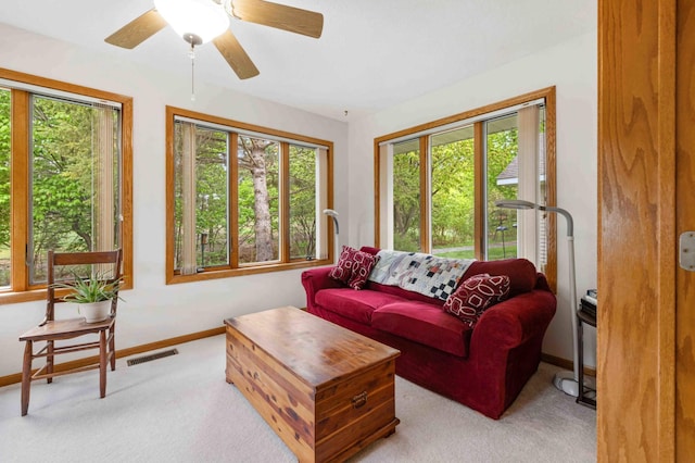 living room with baseboards, light carpet, and ceiling fan
