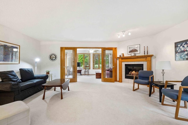 living area with light colored carpet, french doors, a fireplace, and a ceiling fan