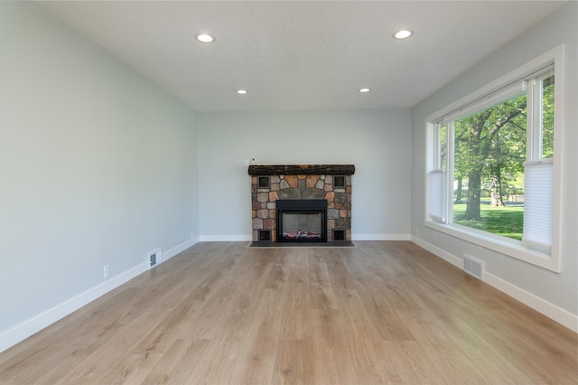 504 Wisconsin Ave N, Frederic, WI 54837 - unfurnished living room featuring recessed lighting, light wood-style flooring, a stone fireplace, and baseboards