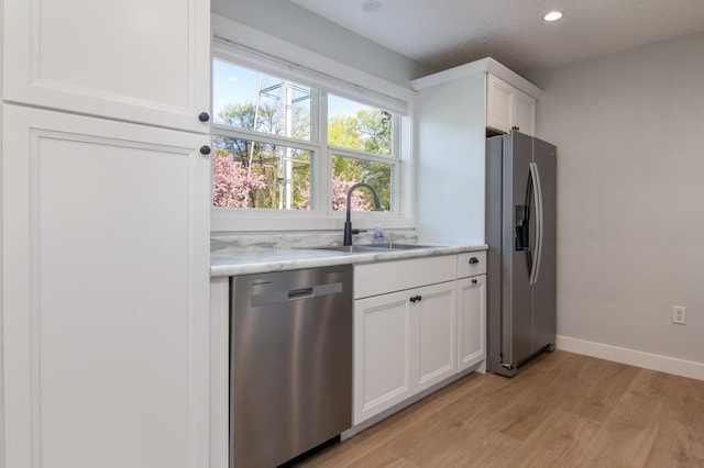 504 Wisconsin Ave N, Frederic, WI 54837 - kitchen featuring appliances with stainless steel finishes, a sink, light wood-type flooring, white cabinetry, and baseboards