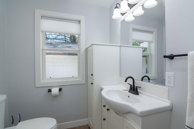 504 Wisconsin Ave N, Frederic, WI 54837 - half bath featuring toilet, plenty of natural light, vanity, and a chandelier