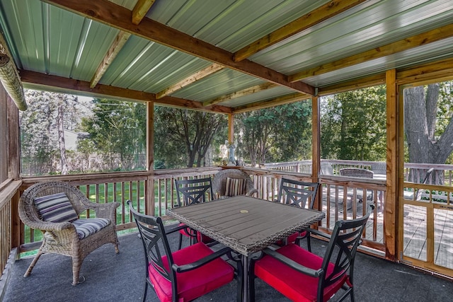 sunroom featuring outdoor dining space and view of wooded area