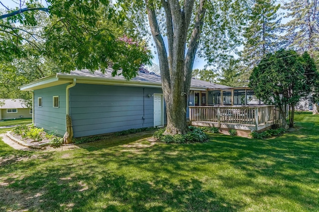back of property featuring a lawn, a wooden deck, and a sunroom