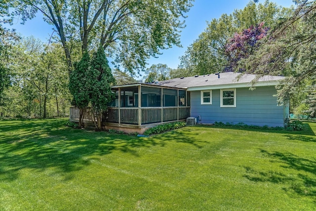 rear view of house featuring a sunroom, a lawn, and central AC