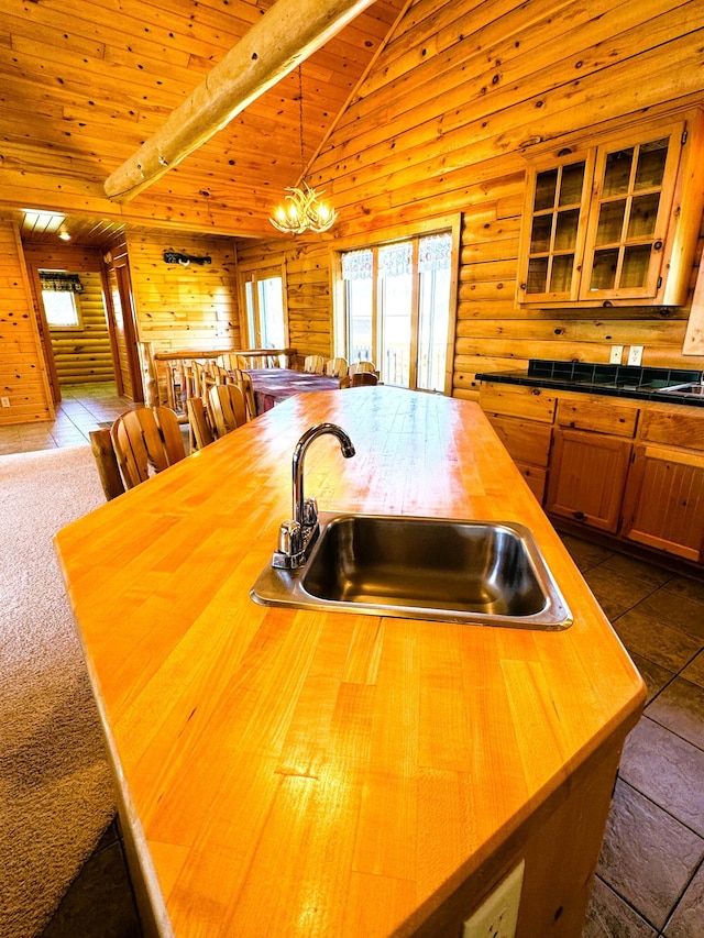 35918 410th Ave SE, Queen Twp, MN 56542 - kitchen with butcher block countertops, a sink, wooden ceiling, glass insert cabinets, and wooden walls