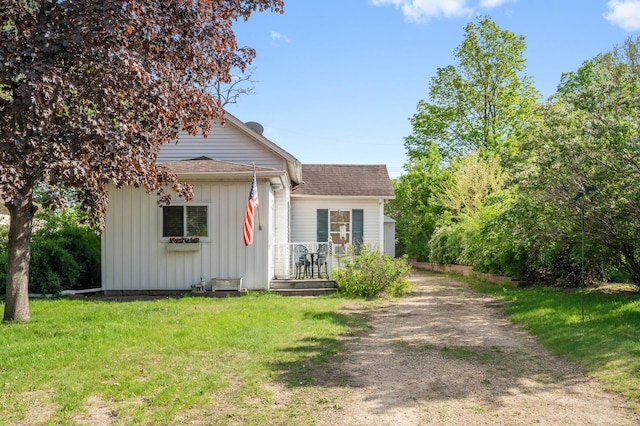 view of front of property with board and batten siding, roof with shingles, a front lawn, and driveway