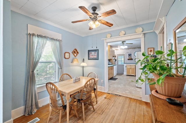 dining space with ceiling fan, light wood finished floors, ornamental molding, and baseboards
