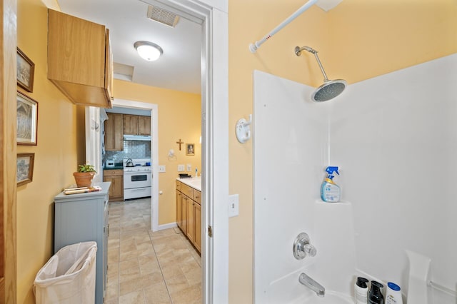 bathroom with backsplash, washtub / shower combination, and vanity