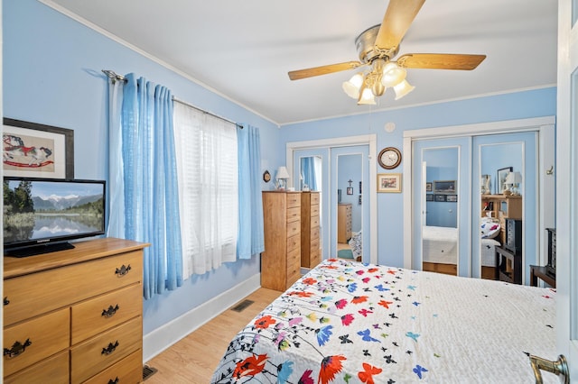 bedroom featuring multiple closets, light wood-type flooring, ornamental molding, baseboards, and a ceiling fan