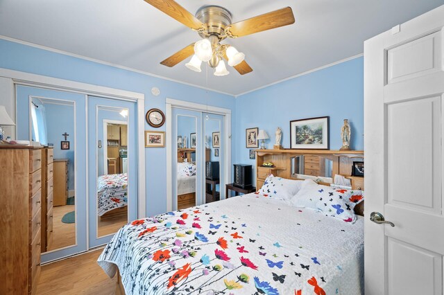 bedroom featuring wood finished floors, crown molding, multiple closets, and a ceiling fan