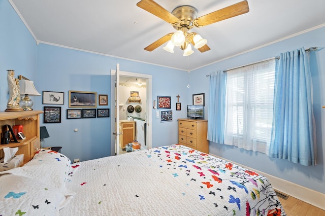 bedroom with crown molding, wood finished floors, a ceiling fan, baseboards, and ensuite bathroom