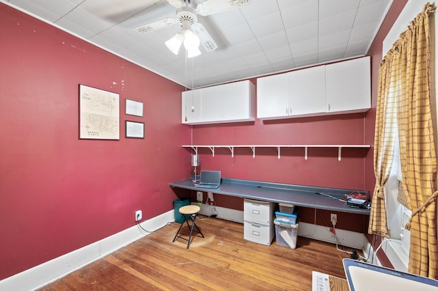 unfurnished office featuring wood finished floors, ceiling fan, and baseboards