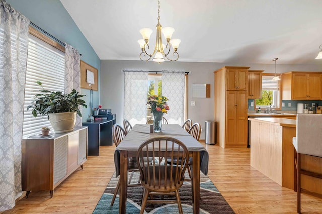 dining room with light wood-style flooring, a chandelier, and vaulted ceiling