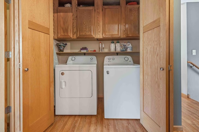 laundry area with washing machine and clothes dryer, cabinet space, and light wood-type flooring