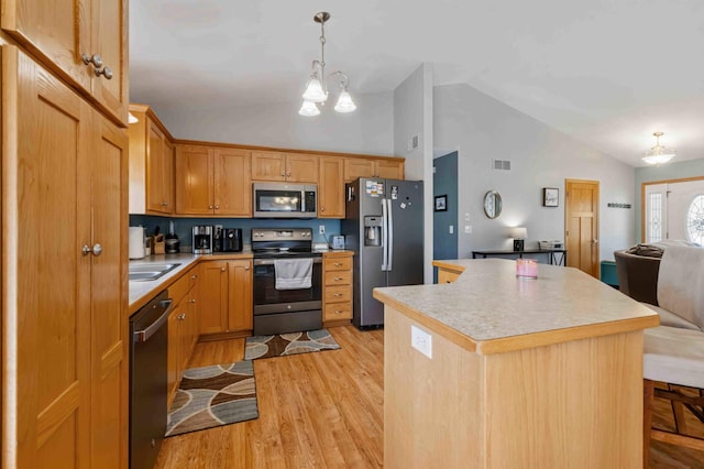 kitchen featuring stainless steel appliances, open floor plan, light wood-style floors, light countertops, and a center island