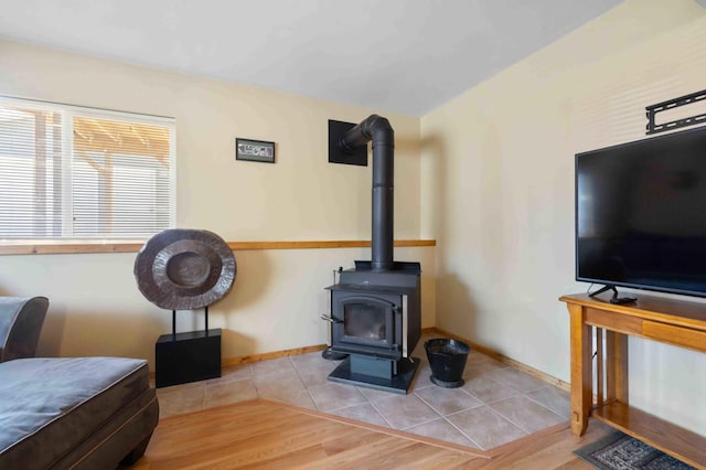 living room featuring a wood stove, wood finished floors, and baseboards