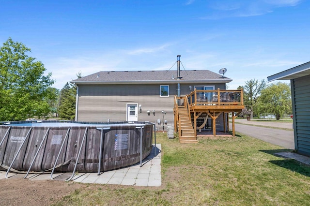 rear view of house featuring a deck, stairs, a lawn, and a shingled roof