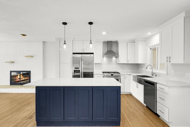 1409 Smith Ave S, West Saint Paul, MN 55118 - kitchen featuring light wood-type flooring, appliances with stainless steel finishes, a brick fireplace, a kitchen island, and wall chimney exhaust hood