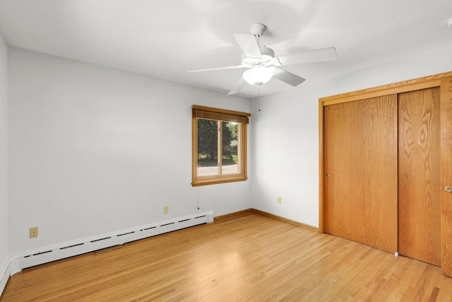 1409 Smith Ave S, West Saint Paul, MN 55118 - unfurnished bedroom featuring wood finished floors, a baseboard heating unit, ceiling fan, and a closet