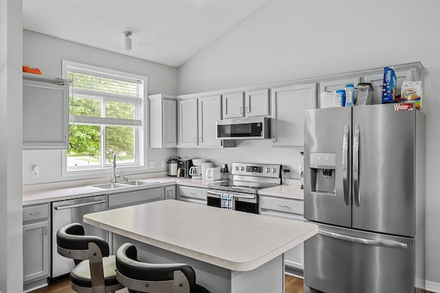 1527 Dublin Ct, Shakopee, MN 55379 - kitchen featuring appliances with stainless steel finishes, a sink, light countertops, vaulted ceiling, and a kitchen island