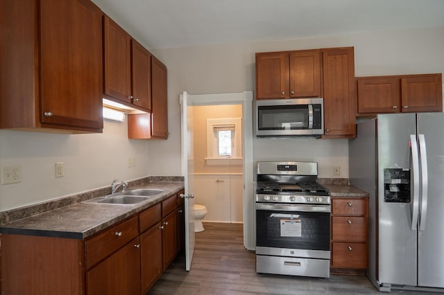 410 Baker St W, Saint Paul, MN 55107 - kitchen featuring stainless steel appliances, a sink, dark countertops, wood finished floors, and brown cabinetry