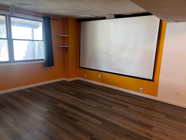 cinema featuring a textured ceiling, dark wood-type flooring, and baseboards