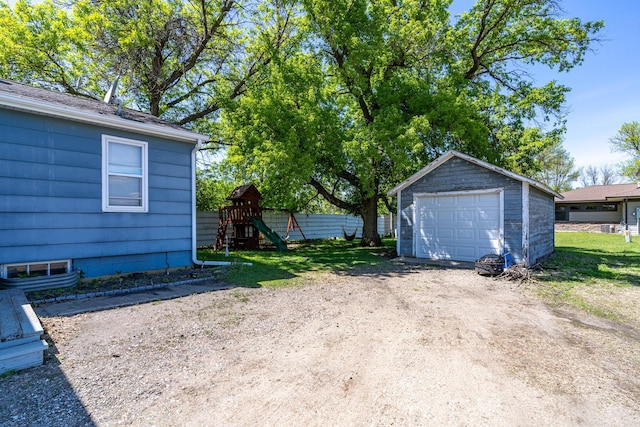 412 Hill Ave, Crookston, MN 56716 - view of yard with a garage, dirt driveway, a playground, and an outdoor structure