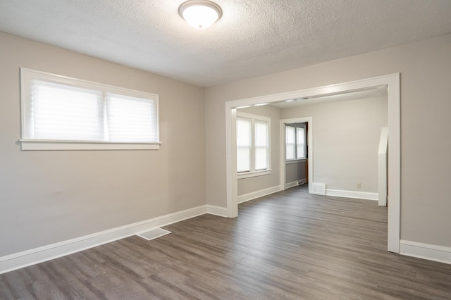 spare room with dark wood-style floors, baseboards, and a textured ceiling