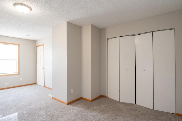unfurnished bedroom with carpet flooring, a textured ceiling, a closet, and baseboards