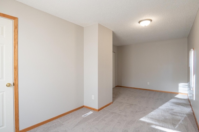spare room featuring carpet flooring, a textured ceiling, and baseboards