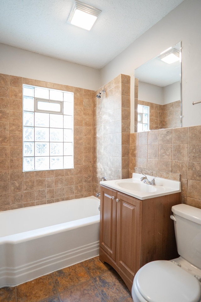 bathroom featuring toilet, tile walls, shower / bath combination, vanity, and tile patterned floors