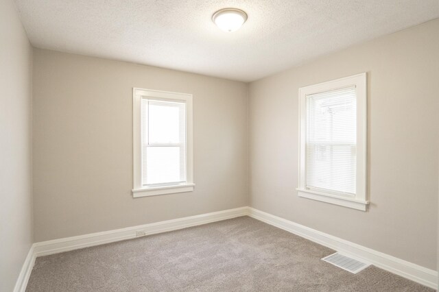 spare room featuring carpet flooring, a textured ceiling, and baseboards