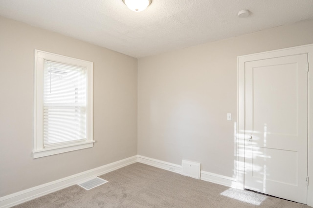 empty room featuring carpet flooring, baseboards, and a textured ceiling