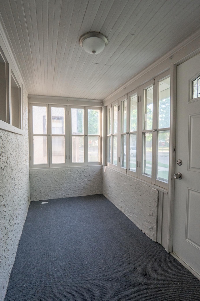 unfurnished sunroom with carpet floors and wooden ceiling