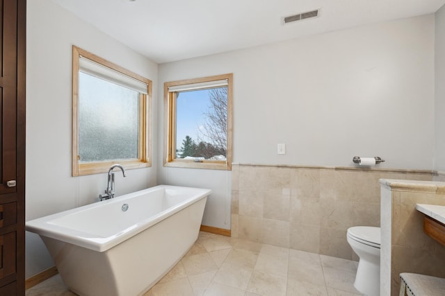 2464 Cottage Grove Dr, Woodbury, MN 55129 - bathroom featuring a freestanding bath, toilet, tile walls, and wainscoting