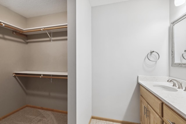 2464 Cottage Grove Dr, Woodbury, MN 55129 - bathroom featuring vanity, baseboards, and a walk in closet