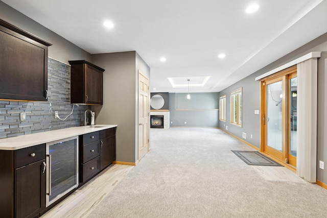 2464 Cottage Grove Dr, Woodbury, MN 55129 - kitchen featuring beverage cooler, dark brown cabinets, decorative backsplash, a glass covered fireplace, and light countertops