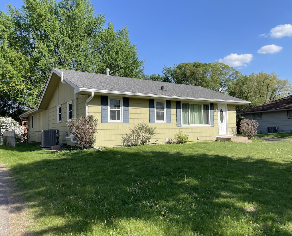 ranch-style house with cooling unit, a front lawn, a shingled roof, and board and batten siding