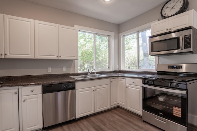 1602 Johnson St NE, Minneapolis, MN 55413 - kitchen with stainless steel appliances, a sink, dark wood-style floors, dark countertops, and white cabinets