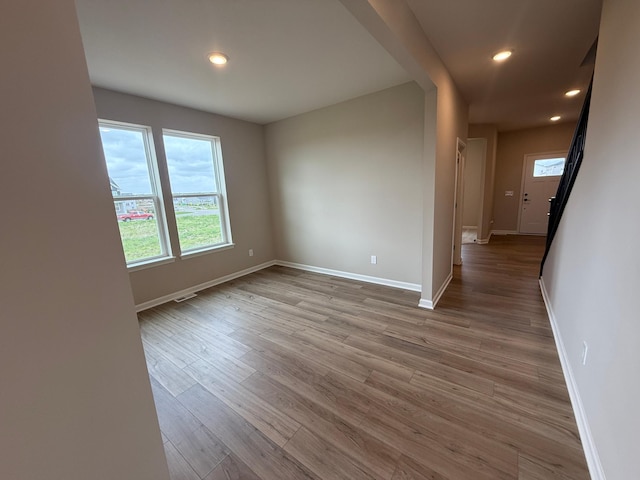 unfurnished room featuring wood finished floors, baseboards, and recessed lighting