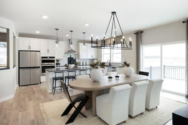 dining space featuring light wood finished floors, recessed lighting, and a chandelier