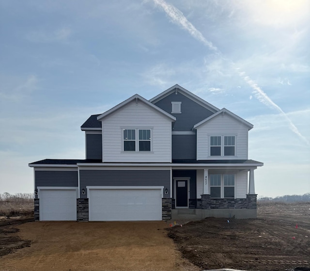 view of front of property featuring stone siding, a porch, an attached garage, and driveway