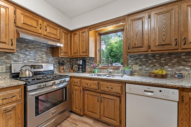 9755 Egret Blvd NW, Coon Rapids, MN 55433 - kitchen with white dishwasher, gas range, under cabinet range hood, brown cabinetry, and decorative backsplash