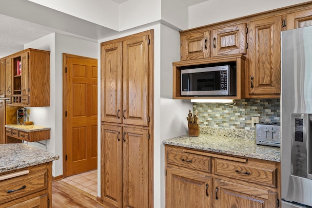 9755 Egret Blvd NW, Coon Rapids, MN 55433 - kitchen with appliances with stainless steel finishes, tasteful backsplash, light stone counters, and brown cabinetry