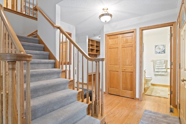 12351 Holly St NW, Coon Rapids, MN 55448 - foyer entrance featuring stairs, light wood-type flooring, a textured ceiling, and baseboards