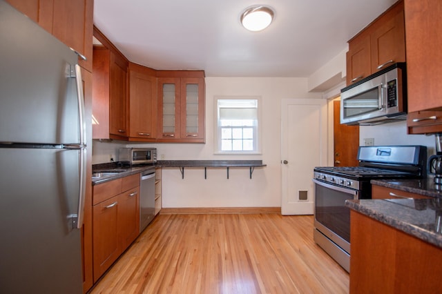1904 Saunders Ave, Saint Paul, MN 55116 - kitchen featuring stainless steel appliances, brown cabinets, light wood finished floors, and glass insert cabinets