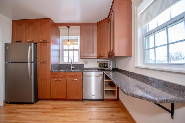 1904 Saunders Ave, Saint Paul, MN 55116 - kitchen with appliances with stainless steel finishes, brown cabinetry, light wood-type flooring, a sink, and dark stone counters